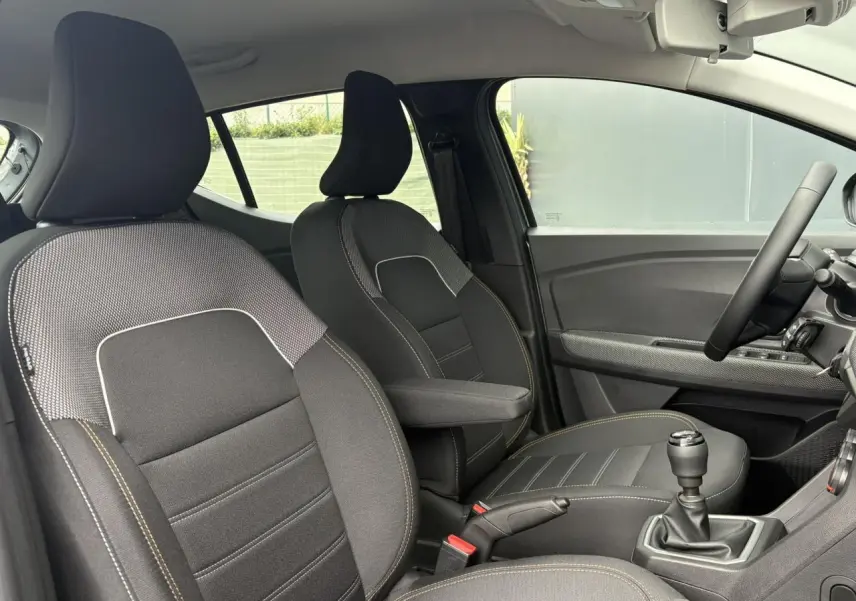 Vue intérieure côté droit du Dacia Sandero Stepway 2025, sièges noirs avec surpiqûres jaunes et accoudoir central.