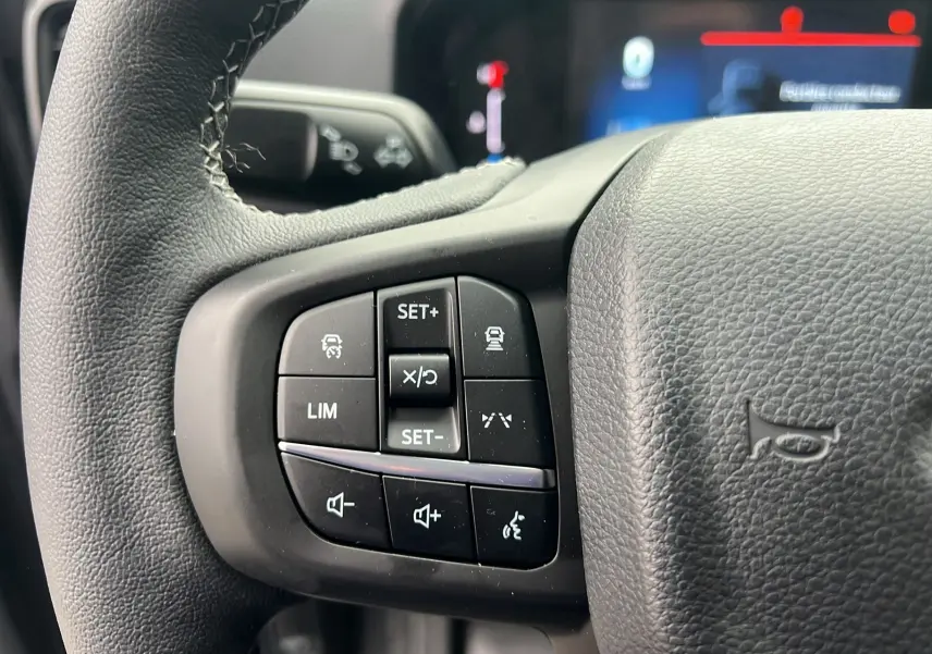 Gros plan sur les commandes au volant du Ford Ranger 2025 gris carbone, mettant en valeur les boutons de régulateur et audio.