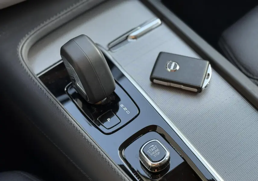 Gros plan sur la console centrale du Volvo XC90 blanc avec levier de vitesse et clé électronique.