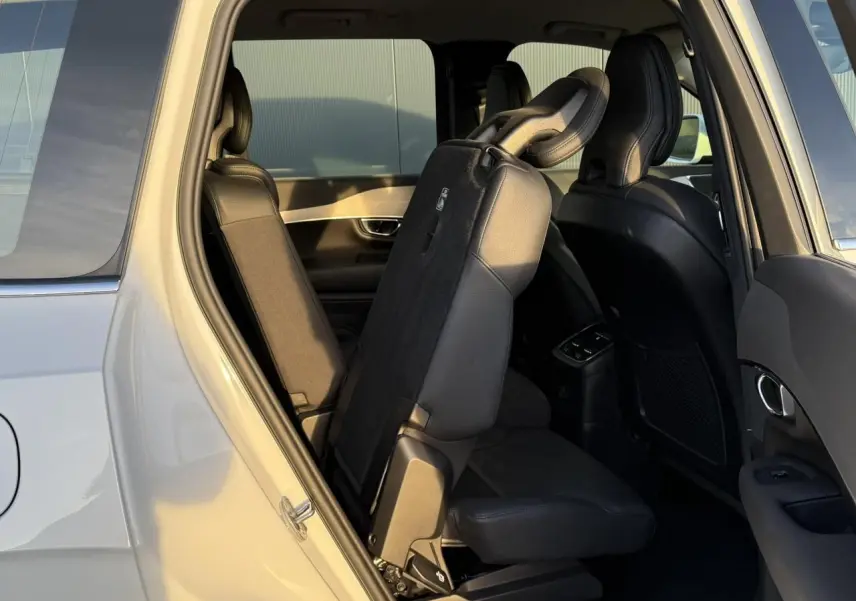 Vue intérieure côté gauche du Volvo XC90 blanc Crystal 2024 montrant les sièges arrière rabattus en partie.