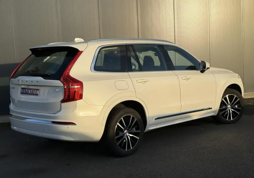 Vue 3/4 arrière droite du Volvo XC90 blanc Crystal 2024 avec jantes alliage noires et détails chromés.