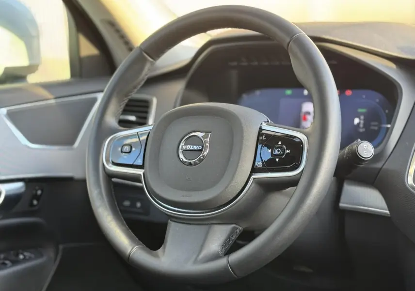 Volant en cuir noir avec commandes intégrées et logo Volvo au centre dans l'habitacle du XC90 2024.