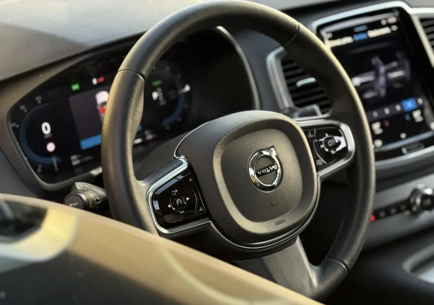 Volant en cuir noir avec logo Volvo au centre, tableau de bord digital et écran tactile du Volvo XC90 T8 hybride 2024.