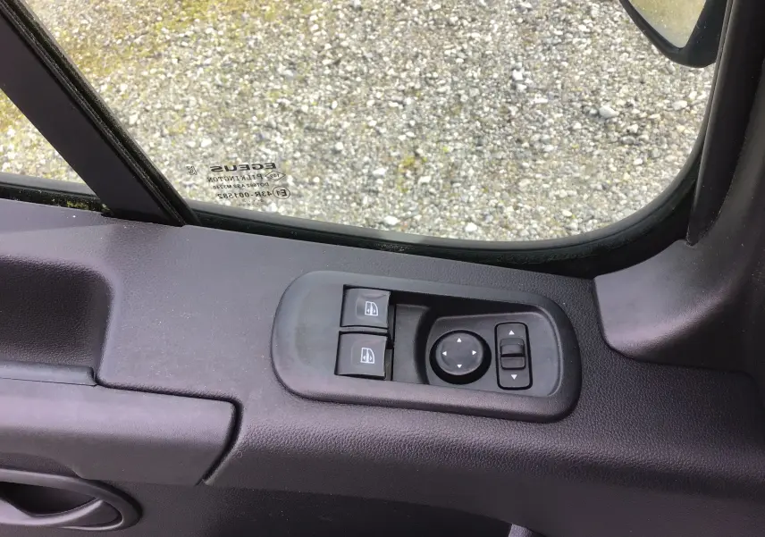 Vue rapprochée du panneau de commandes des vitres et rétroviseurs côté gauche du Renault Master blanc, intérieur noir.