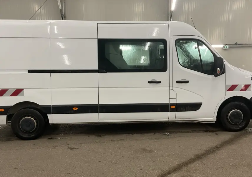 Vue latérale droite d’un Renault Master cabine approfondie blanc avec marquages rouges réfléchissants et vitres teintées.