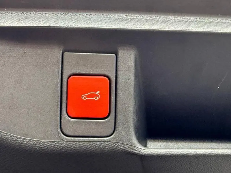 Bouton rouge d'ouverture électrique du coffre sur la porte intérieure d'une DS4 Gris Platinium 2023.