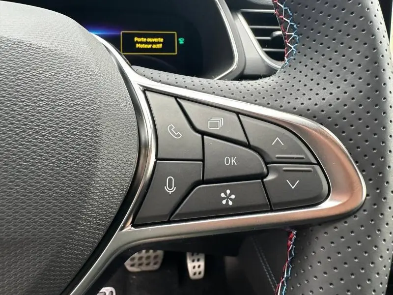 Gros plan sur les commandes au volant côté droit du Renault Captur 1.8 E-Tech hybride 2026 avec surpiqûres bleu, blanc, rouge.