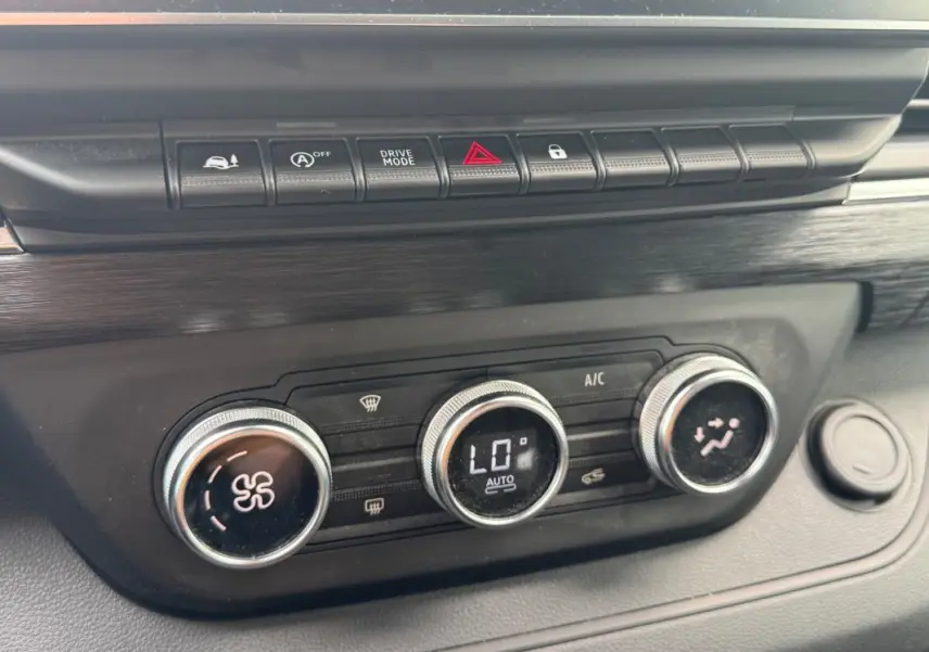 Gros plan sur la console centrale du Renault Trafic Fourgon gris foncé, montrant les commandes de climatisation et les boutons de fonction.