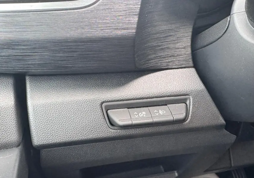 Détail intérieur montrant les commandes de réglage des feux et du tableau de bord du Renault Trafic Fourgon gris foncé.