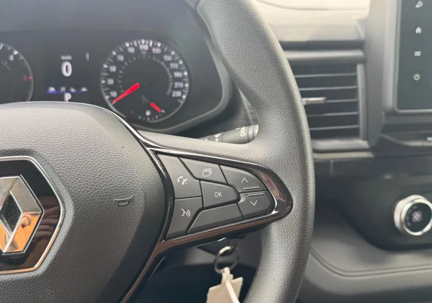 Vue rapprochée du volant Renault Trafic Fourgon gris foncé 2024, avec commandes multifonctions et tableau de bord digital.