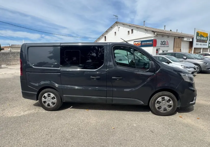 Vue latérale droite d’un Renault Trafic Fourgon gris foncé avec vitres surteintées, porte latérale coulissante et jantes acier.