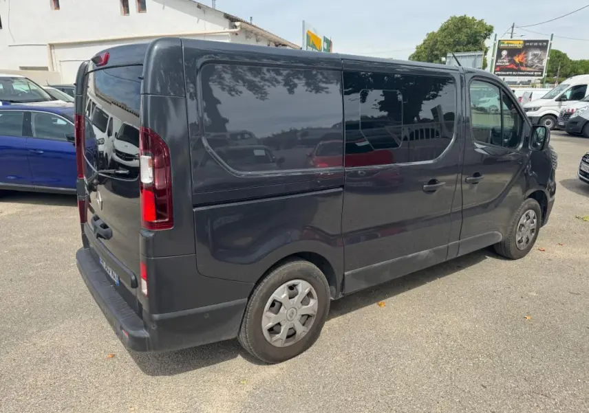 Vue 3/4 arrière droite d’un Renault Trafic fourgon gris foncé avec vitres surteintées et porte latérale fermée.