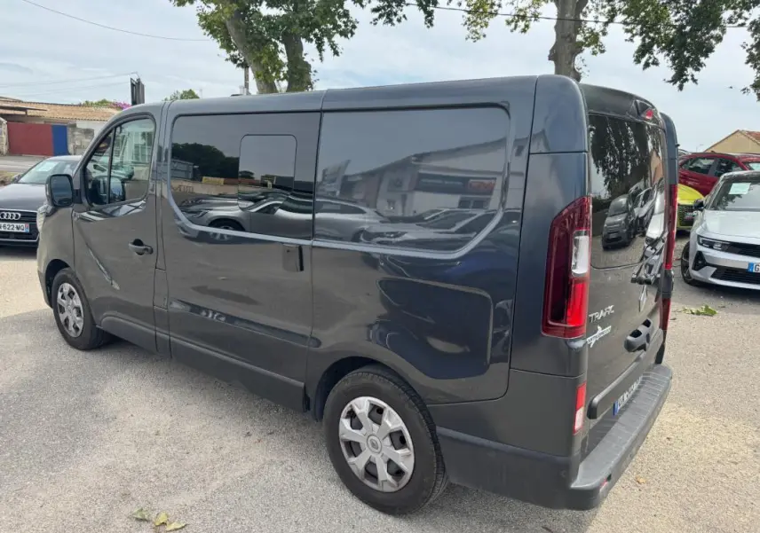 Vue 3/4 arrière droite d’un Renault Trafic Fourgon gris foncé avec vitres surteintées et porte latérale visible.