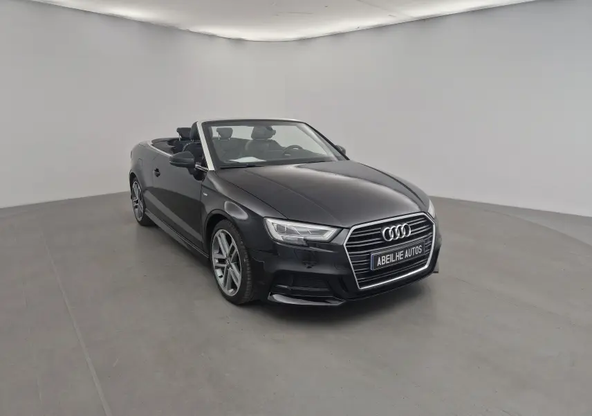 Audi A3 Cabriolet noir vue 3/4 avant droit, capote ouverte, intérieur cuir noir et jantes alliage 18 pouces.