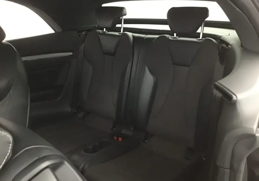 Vue intérieure arrière des sièges noirs en cuir de l'Audi A3 Cabriolet 2020, avec accoudoir central et appuie-têtes.