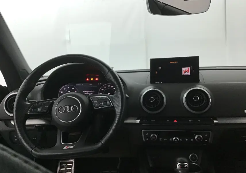 Vue intérieure du tableau de bord noir de l'Audi A3 Cabriolet 2020, avec volant sport et écran central allumé.