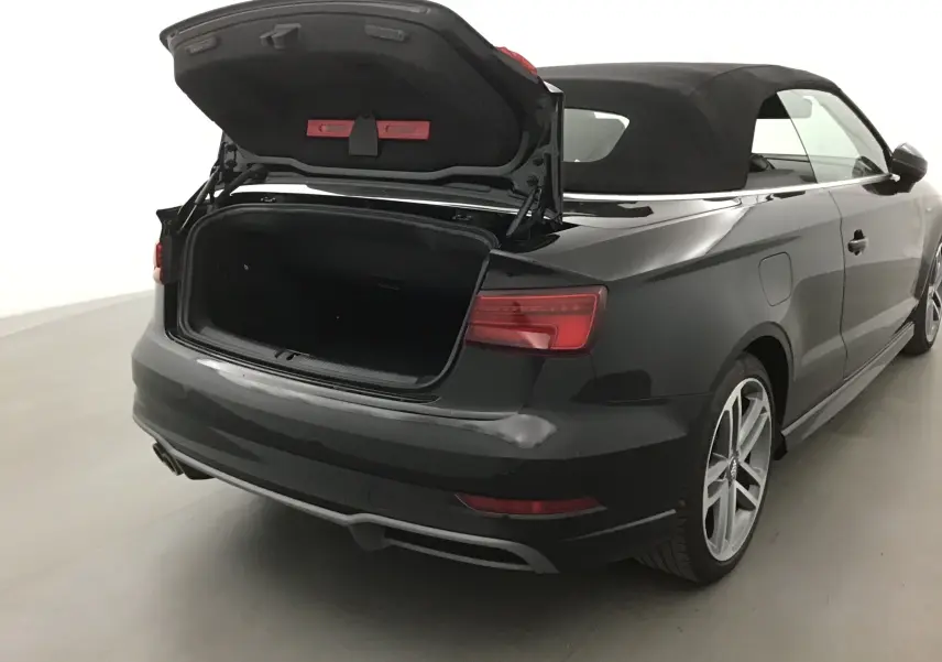 Vue 3/4 arrière droite d'une Audi A3 Cabriolet noire 2020 avec coffre ouvert et capote en toile noire.