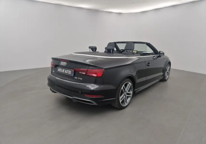 Audi A3 Cabriolet noir vue 3/4 arrière droit, capote électrique repliée et jantes alliage 18 pouces visibles.