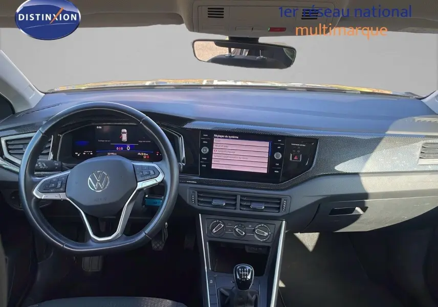 Vue intérieure frontale du tableau de bord et volant noir du Volkswagen Taigo gris cendre 2022 avec boîte manuelle.