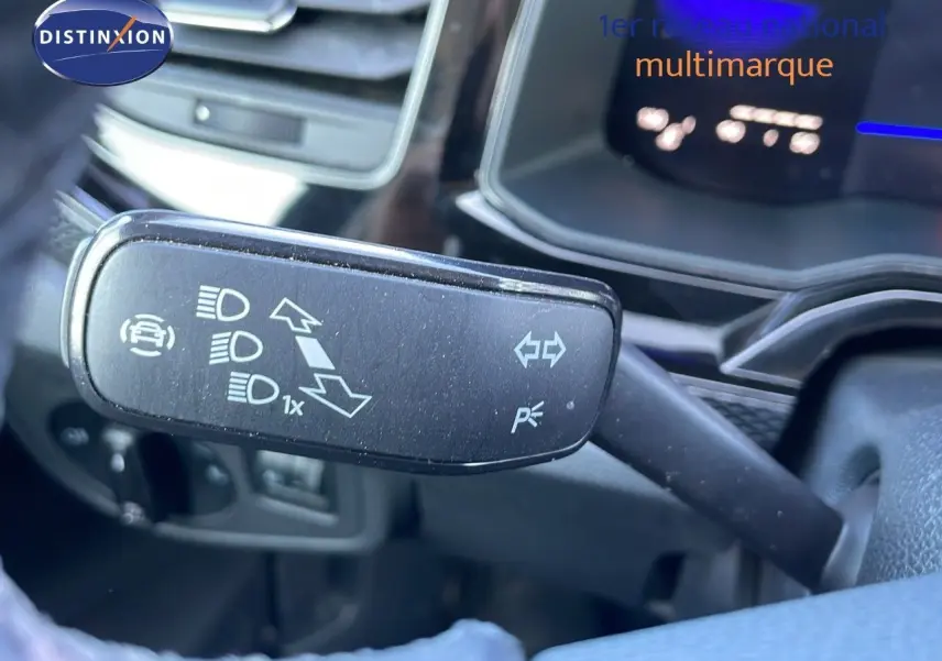 Gros plan sur la commande des clignotants et feux d'un Volkswagen Taigo gris cendre, tableau de bord en arrière-plan.