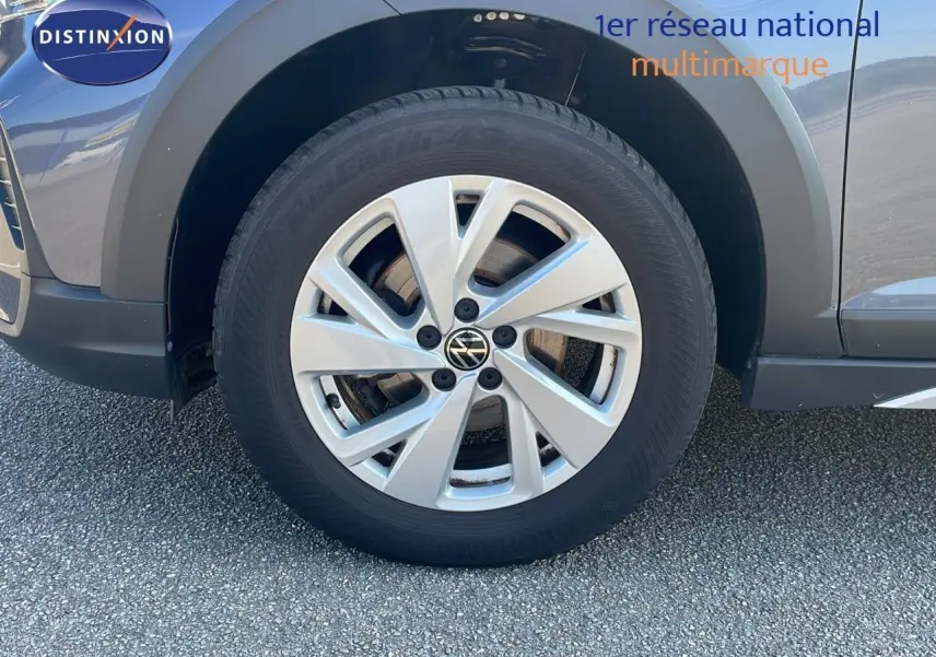 Gros plan sur la roue avant gauche d'un Volkswagen Taigo gris cendre, soulignant la jante alliage 16 pouces.