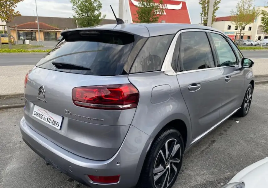 Vue 3/4 arrière droite d'une Citroën C4 Spacetourer gris Artense avec jantes alliage bi-ton et toit noir.