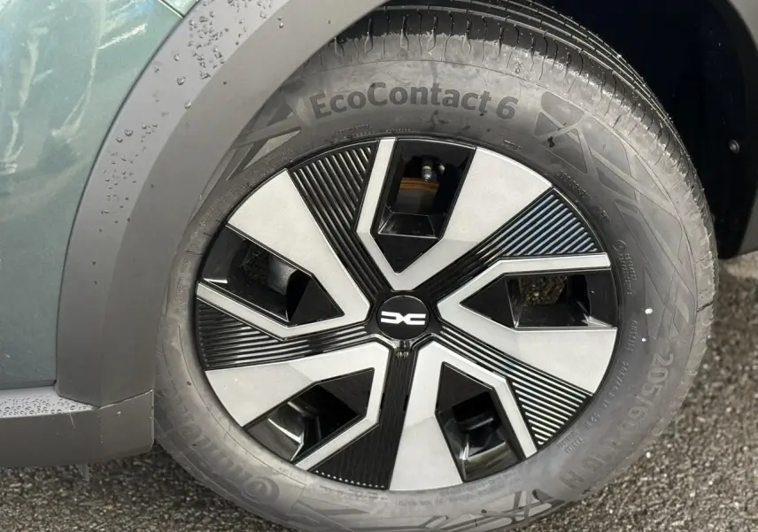 Gros plan sur la roue avant gauche du Dacia Sandero Stepway 2025 vert cèdre avec enjoliveur noir et gris au design géométrique.