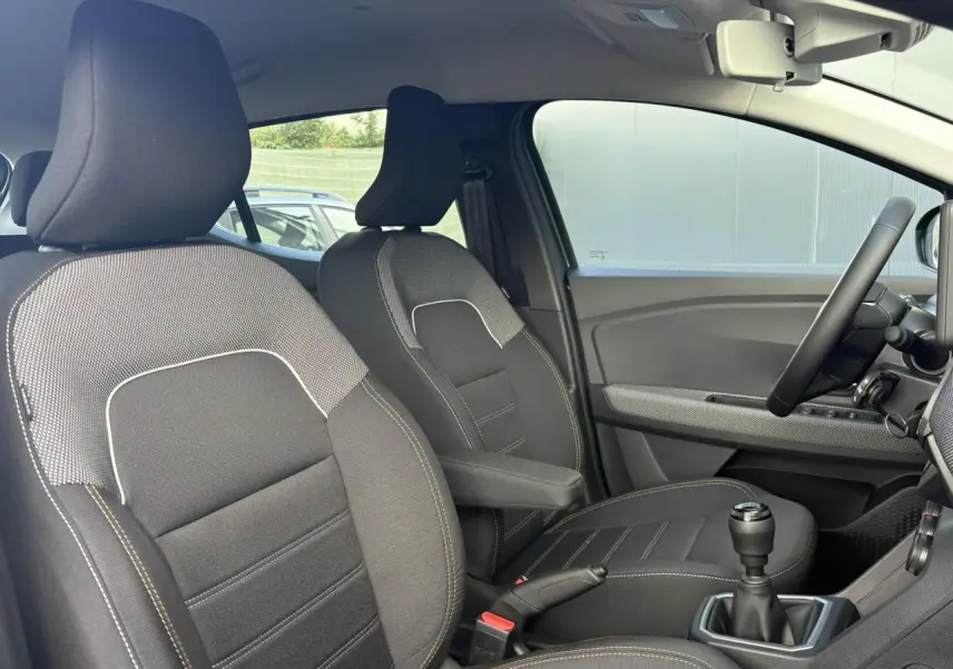 Vue intérieure côté conducteur de la Dacia Sandero Stepway 2025, sièges noirs avec accoudoir central et volant Soft Feel.