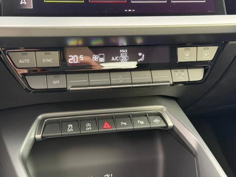 Vue rapprochée du tableau de bord et commandes de climatisation de l'Audi A3 Sportback blanc Arkona 2024.