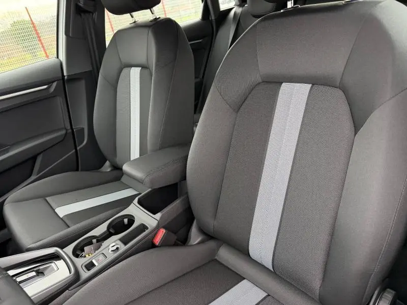 Vue intérieure rapprochée des sièges avant en tissu noir avec bande centrale grise de l'Audi A3 Sportback 2024.