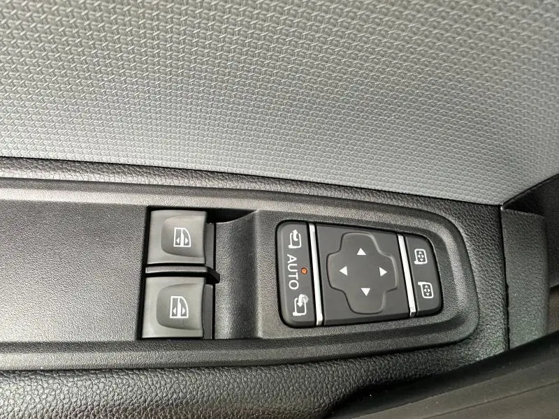 Commandes électriques des vitres et rétroviseurs sur la porte côté conducteur du Nissan Townstar blanc Minéral 2024.