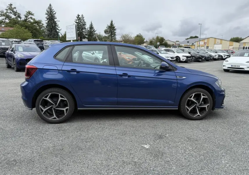 Profil côté gauche d'une Volkswagen Polo 1.0 TSI R-Line bleu métallisé avec jantes alliage 17 pouces sur parking.