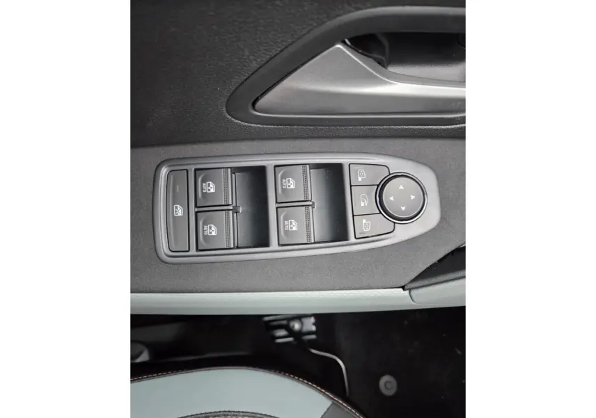 Gros plan sur les commandes des vitres électriques et rétroviseurs sur la porte côté conducteur du Dacia Bigster blanc glacier.