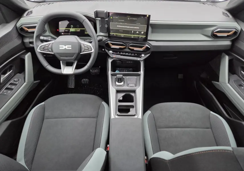 Vue intérieure avant du Dacia Bigster 2025 avec tableau de bord moderne, écran tactile et sellerie gris foncé.