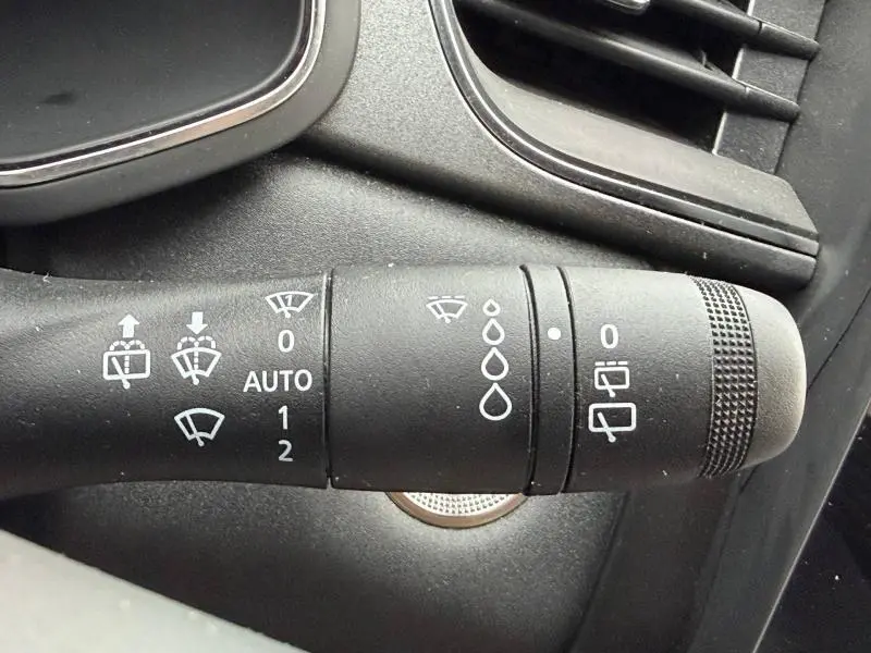 Gros plan sur la commande des essuie-glaces du Renault Captur 2025, détails des réglages et symboles blancs sur fond noir.