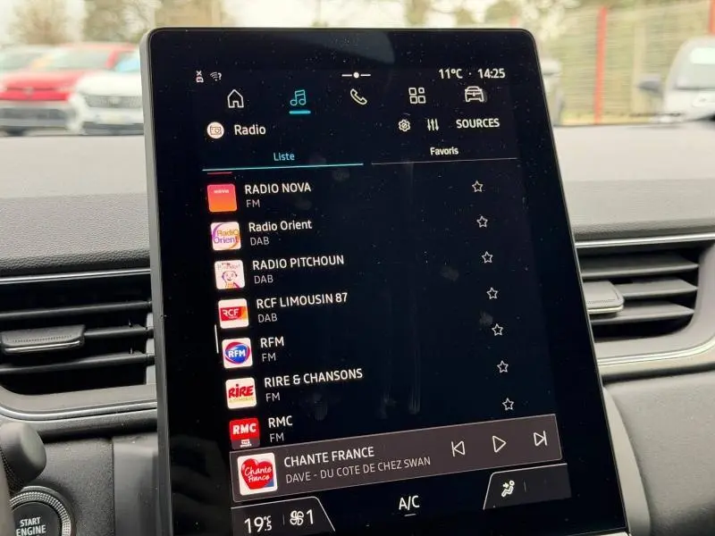 Écran tactile central du tableau de bord du Renault Captur 2025 affichant les stations radio, intérieur noir.