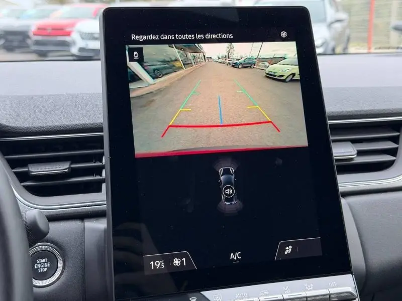 Vue intérieure du tableau de bord du Renault Captur 2025, écran central affichant la caméra de recul avec vue arrière sur un parking.