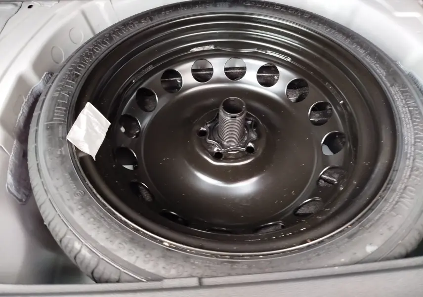 Gros plan sur la roue de secours noire du coffre d'une SEAT ARONA blanc candy 2023, version essence 1.0 TSI.