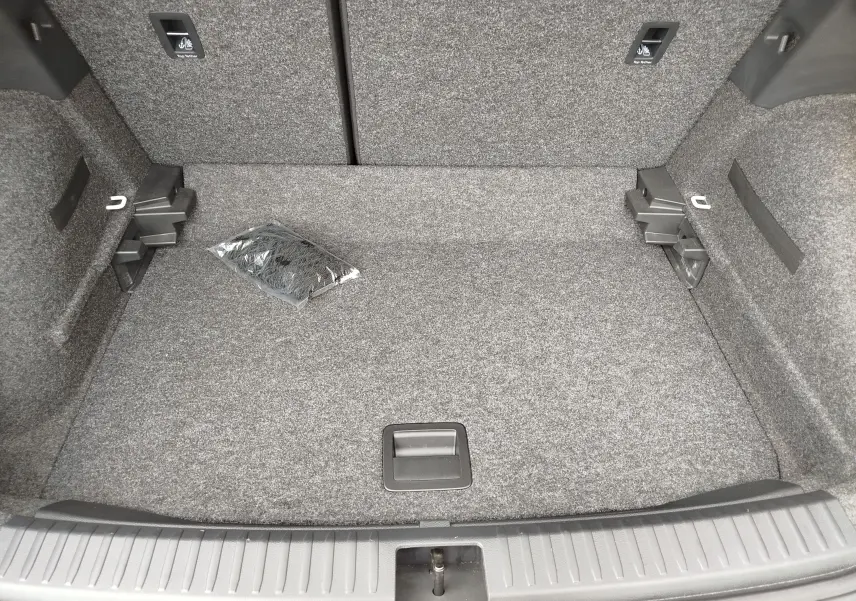 Coffre ouvert vu de dessus du SEAT Arona blanc candy 2023, intérieur gris avec filet de rangement emballé.