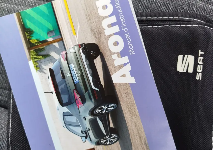 Vue 3/4 arrière d'une SEAT Arona gris métallisé garée sur un sol béton avec un mur coloré en arrière-plan.