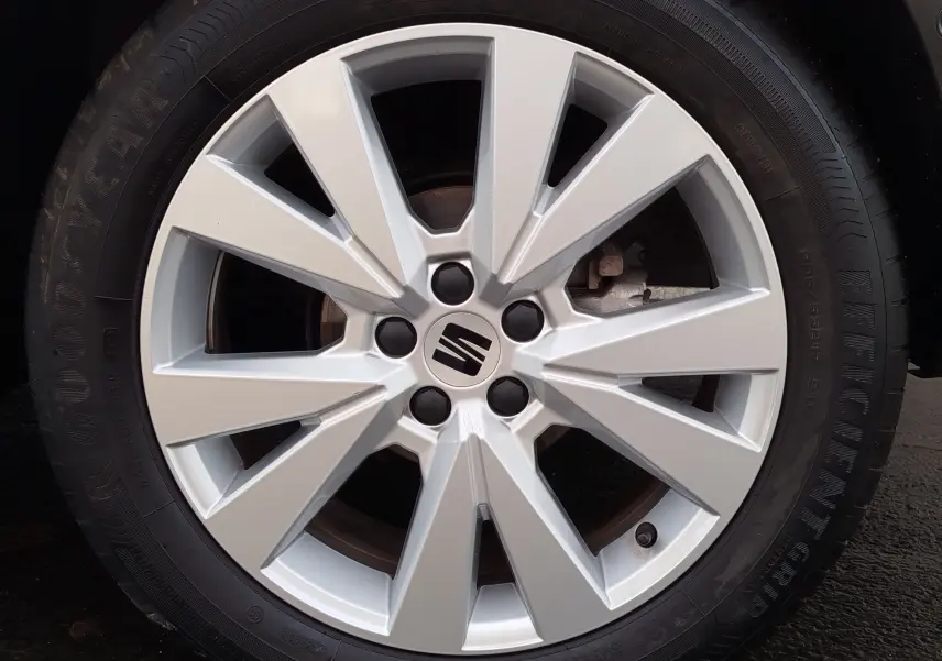 Gros plan sur la jante alliage argentée du SEAT ARONA blanc candy, mettant en valeur le logo central de la marque.