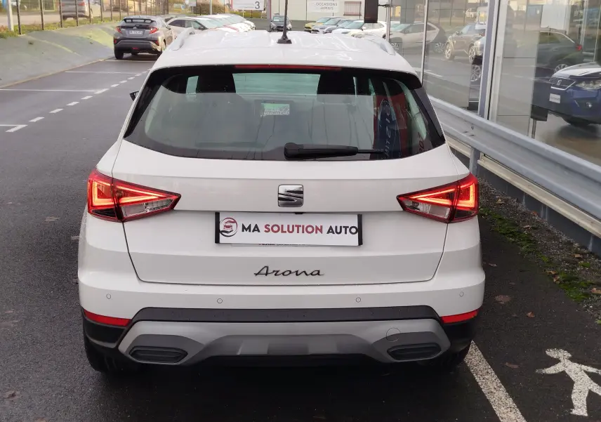 Vue arrière d'une SEAT Arona blanc candy 2023 avec feux LED allumés et logo distinctif sur le hayon.