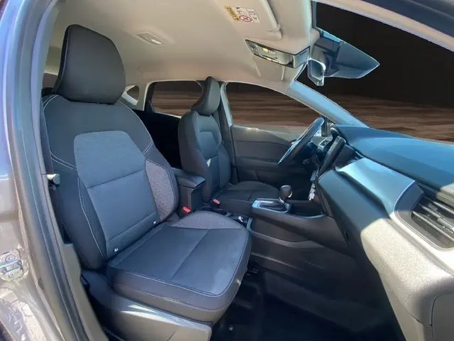 Vue intérieure côté conducteur du Renault Captur E-Tech Full Hybrid 145 Evolution 2023, sièges tissu noir et tableau de bord moderne.