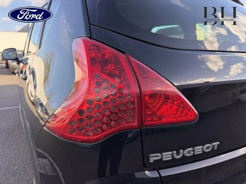 Gros plan sur le feu arrière droit d’un Peugeot 3008 noir Perla Nera, avec reflet du ciel sur la carrosserie.