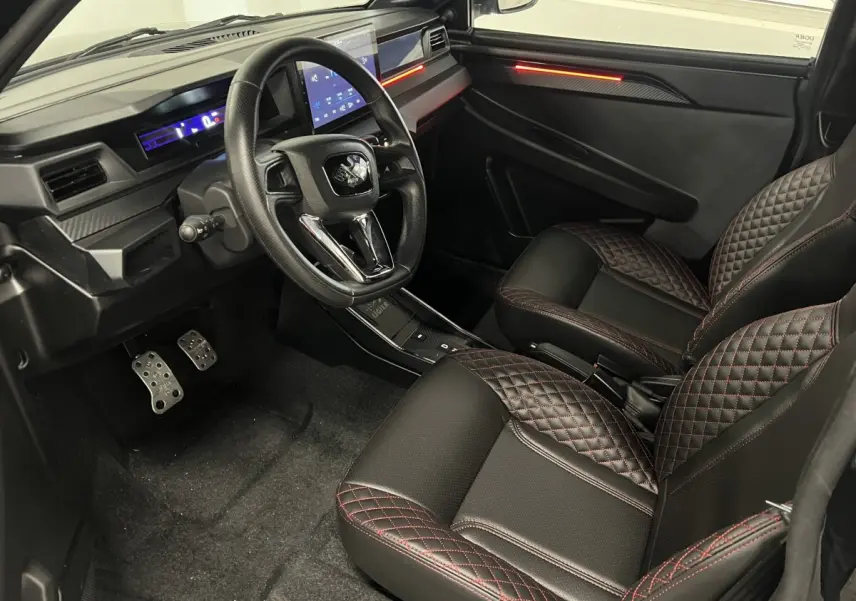 Vue intérieure côté conducteur de la Ligier JS50 Ultimate 2026, sièges noirs avec surpiqûres rouges et tableau de bord digital.