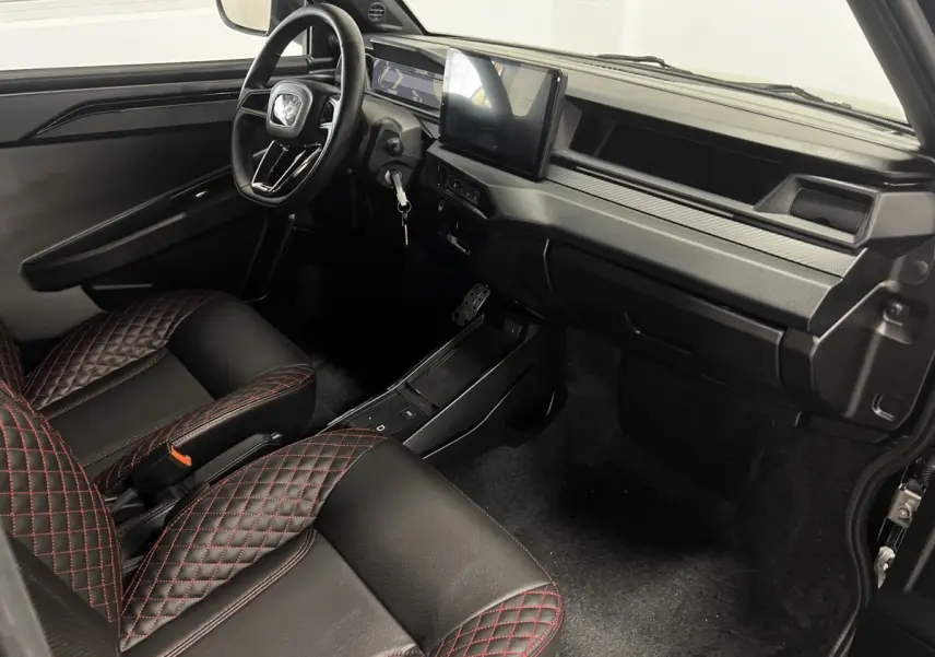 Vue intérieure côté conducteur de la LIGIER JS50 noire avec sièges Ultimate à surpiqûres rouges et écran tactile central.