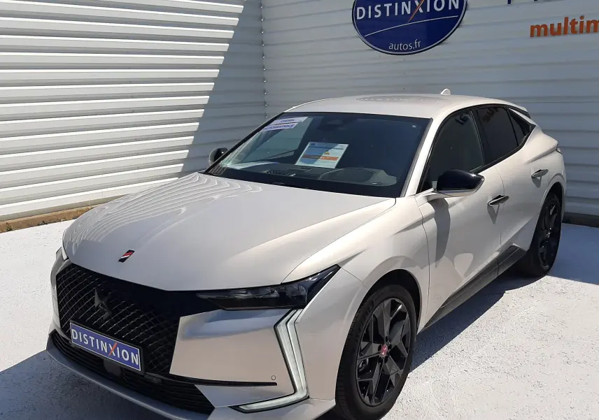 DS4 diesel cristal pearl vue 3/4 avant droit, jantes noires et calandre distinctive DS sous un ciel ensoleillé.