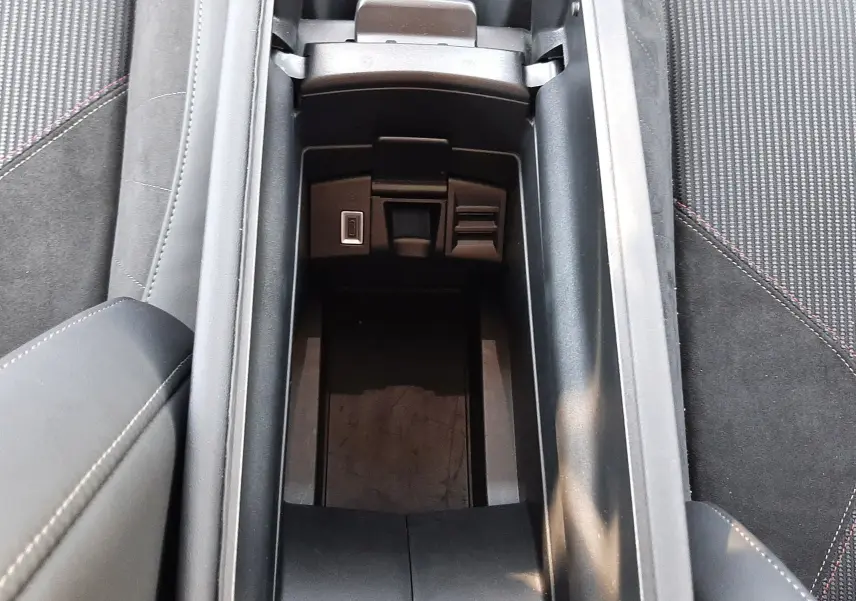 Vue plongeante sur le rangement central ouvert de la DS4 2024, intérieur noir avec prises USB et finition sobre.