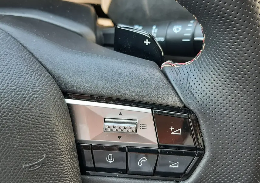 Gros plan sur la commande droite du volant en cuir perforé noir avec surpiqûres rouges du DS4 Cristal Pearl 2024.