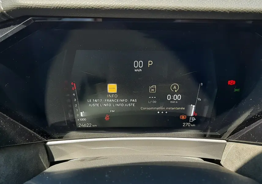 Tableau de bord numérique du DS4 2024, affichant la vitesse à 0 km/h et la consommation instantanée, vue frontale rapprochée.